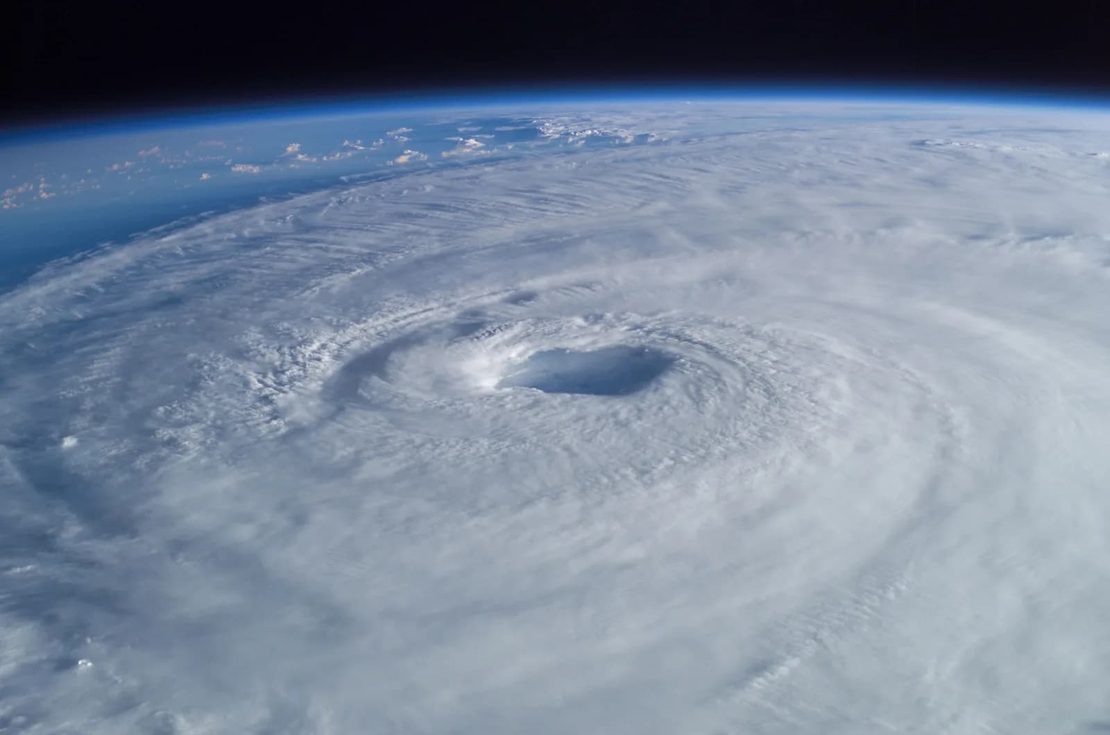 Hurricane Isabel seen from the International Space Station: a white spiral of cloud with a dark, clear eye in the middle, under the curve of the Earth and black space