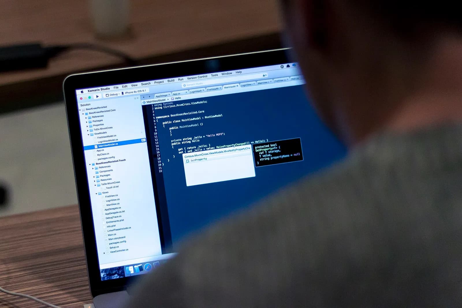 A person seen from behind working at a laptop with a code editor open