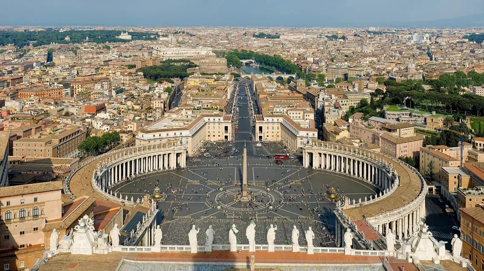 La plaza de San Pedro en la Ciudad del Vaticano vista desde la cúpula de la basílica, con sus columnatas curvas, el obelisco en el centro y los tejados de Roma al fondo