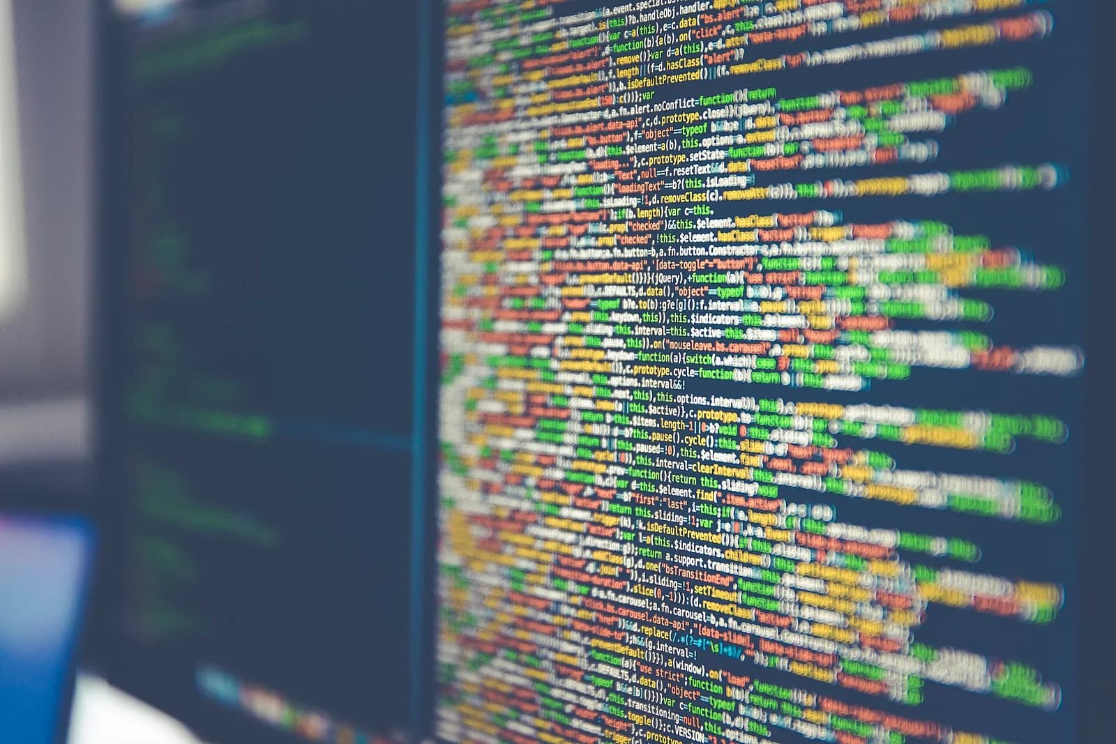 Des lignes de code source colorées sur un écran, floues sur les bords