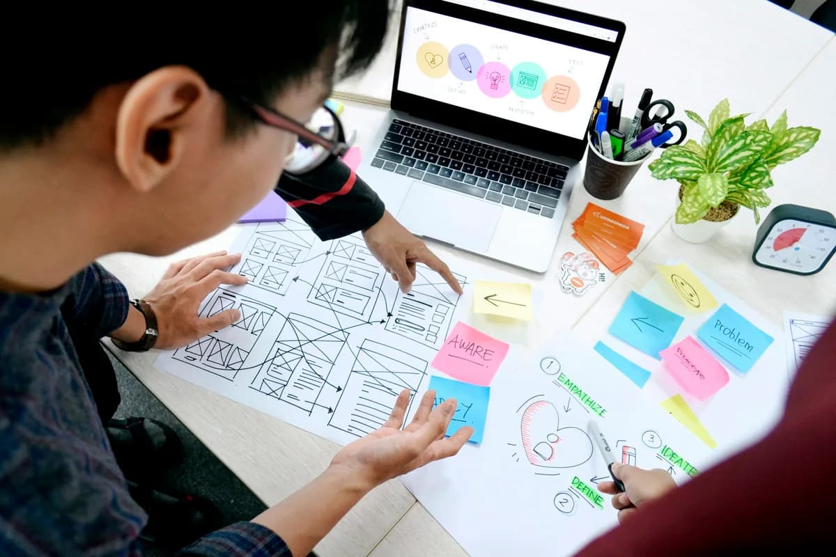 Designers reviewing paper wireframes at a desk