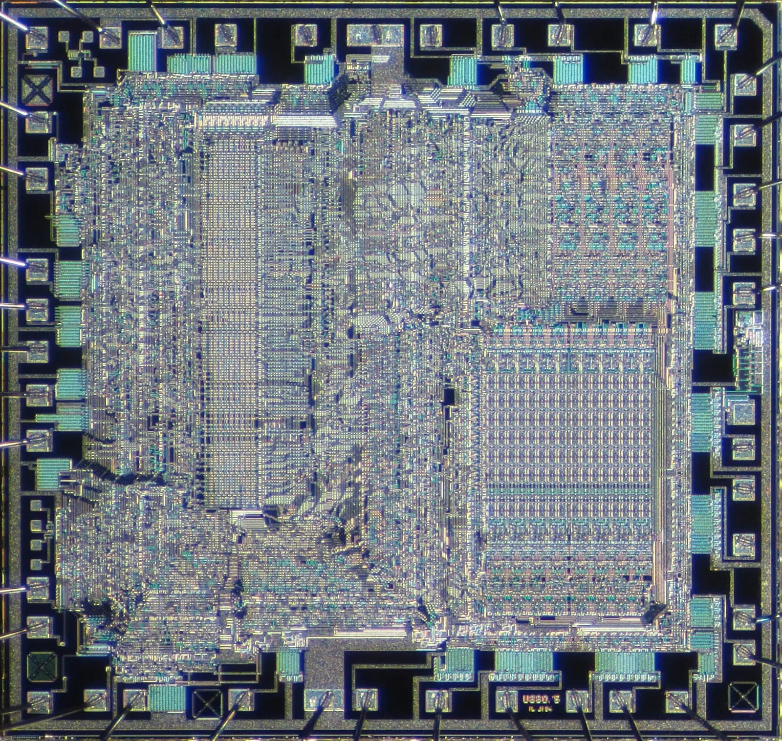 Microscope photo of the bare silicon die of a Z80-compatible 8-bit microprocessor: dense grey-blue circuitry in rectangular blocks, ringed by square bonding pads