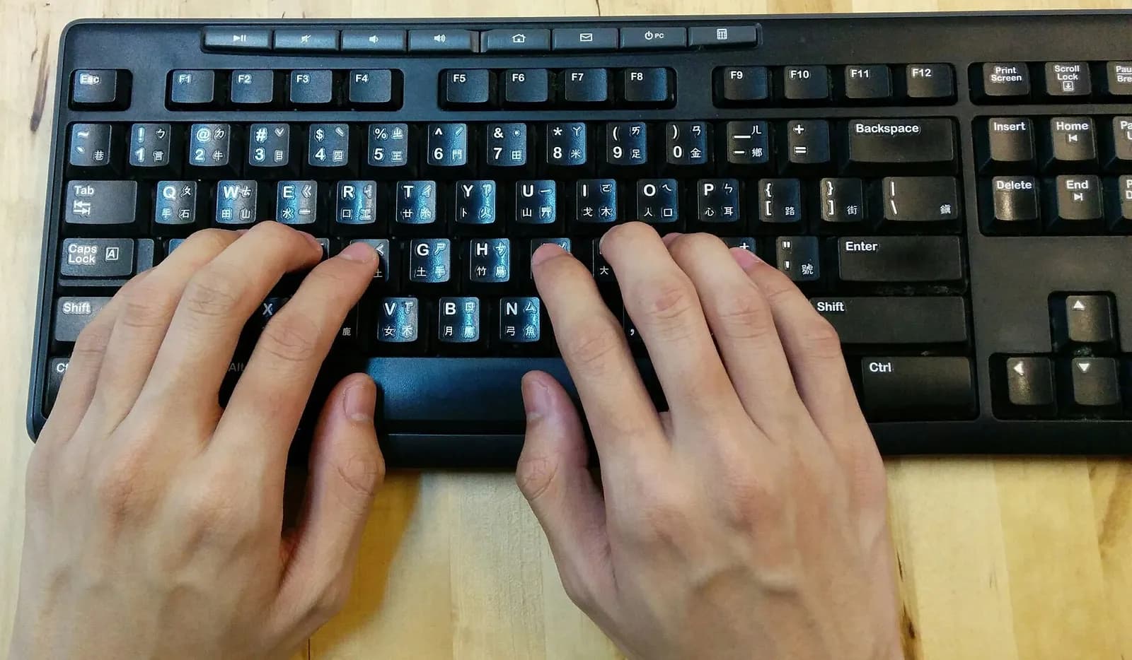 Close-up of two hands resting on a black keyboard in the typing position