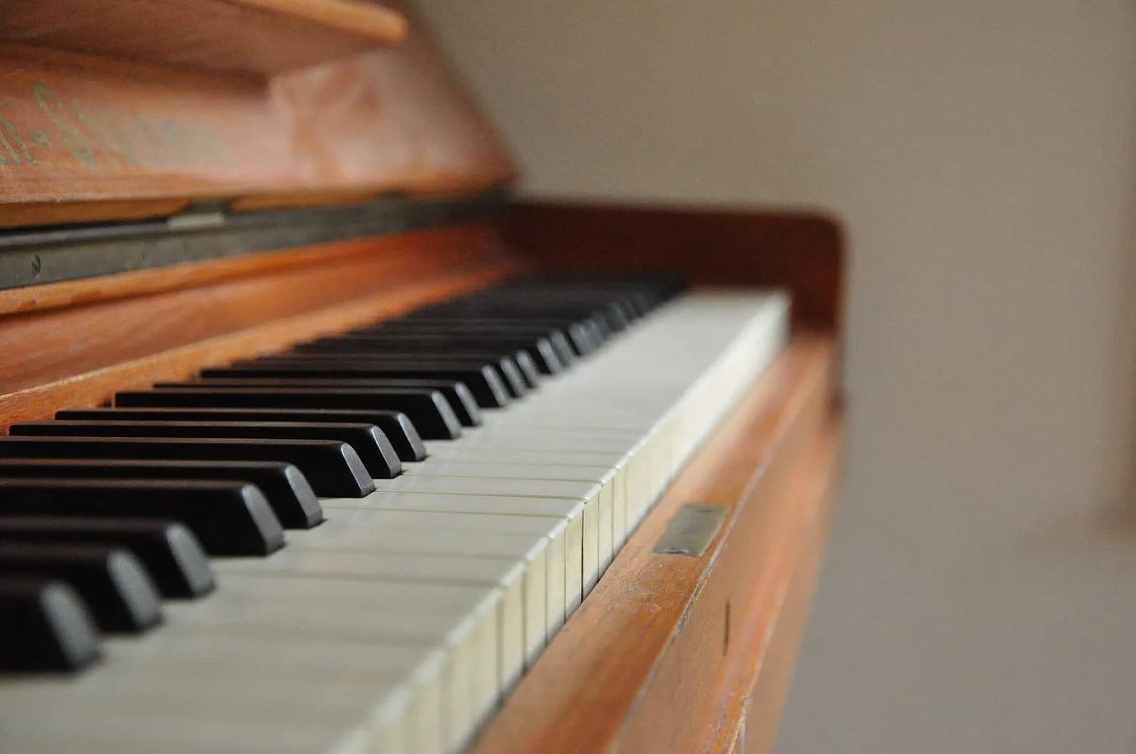 Close-up of the black and white keys of a wooden upright piano, receding out of focus